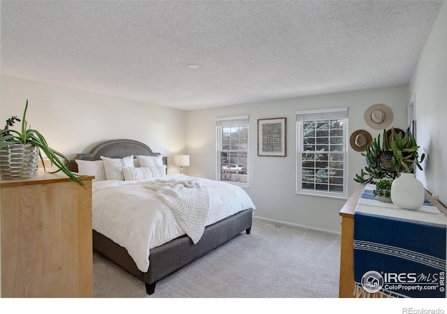 bedroom with light colored carpet and a textured ceiling