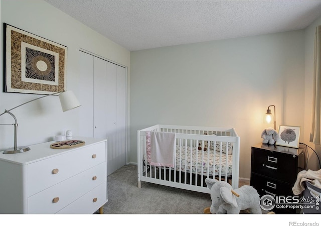 carpeted bedroom featuring a crib, a textured ceiling, and a closet