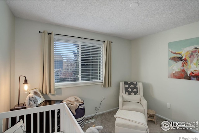 carpeted bedroom with a crib and a textured ceiling