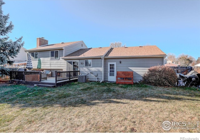 rear view of house with a lawn, a wooden deck, and central AC