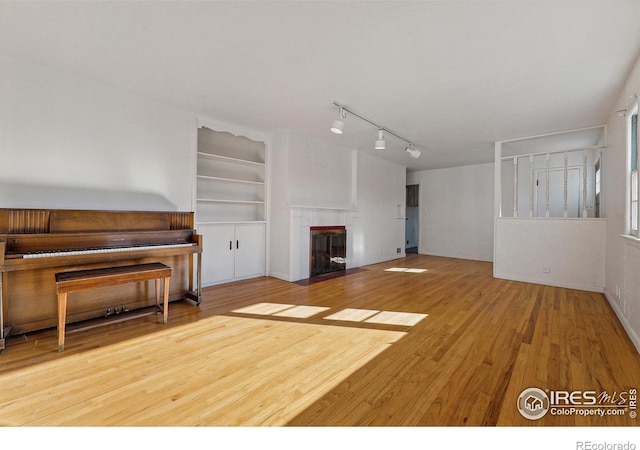 living room with hardwood / wood-style floors, built in shelves, and a tile fireplace