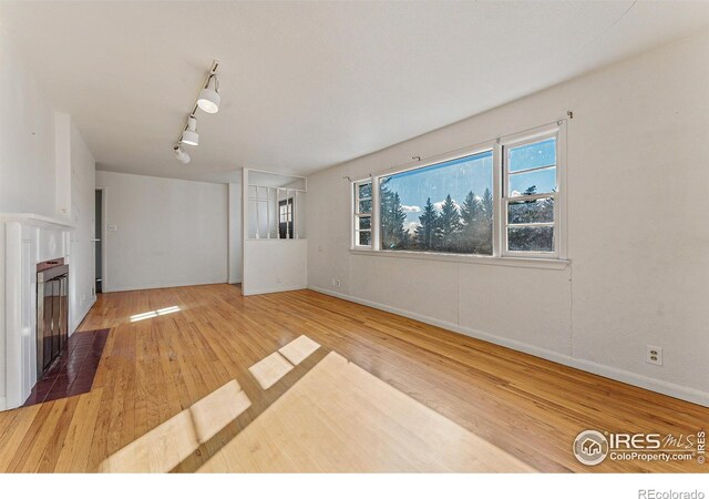 unfurnished living room with hardwood / wood-style floors and rail lighting