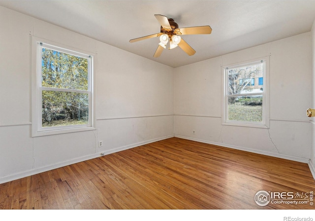 spare room with a wealth of natural light, hardwood / wood-style floors, and ceiling fan