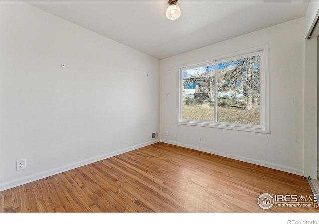 spare room featuring wood-type flooring and vaulted ceiling