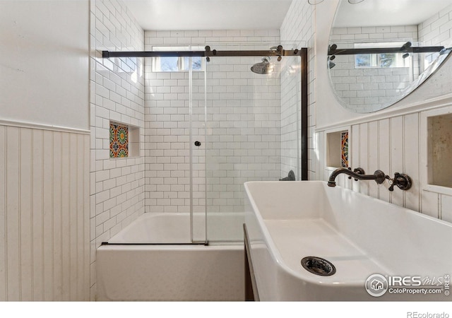 bathroom with sink and bath / shower combo with glass door