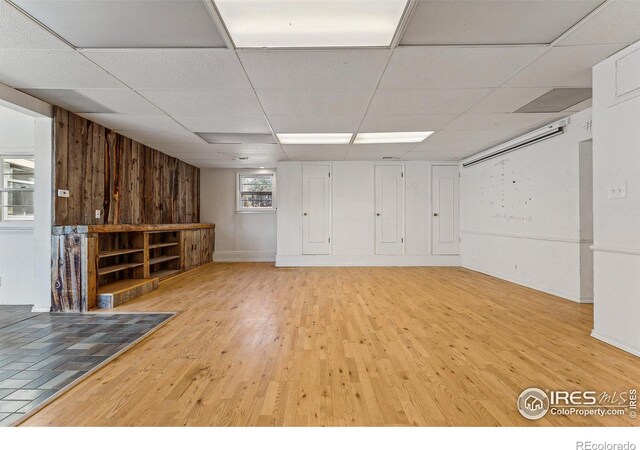 basement with a paneled ceiling, hardwood / wood-style flooring, and wood walls