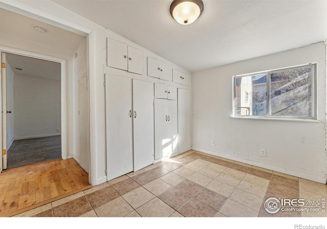 unfurnished bedroom featuring light hardwood / wood-style floors, lofted ceiling, and a closet