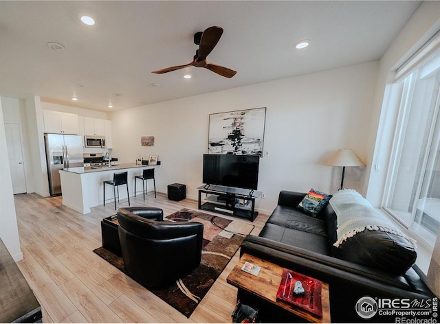 living room featuring light wood-type flooring and ceiling fan