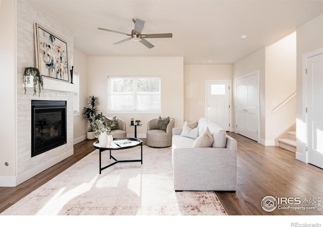 living room with hardwood / wood-style floors, a large fireplace, and ceiling fan