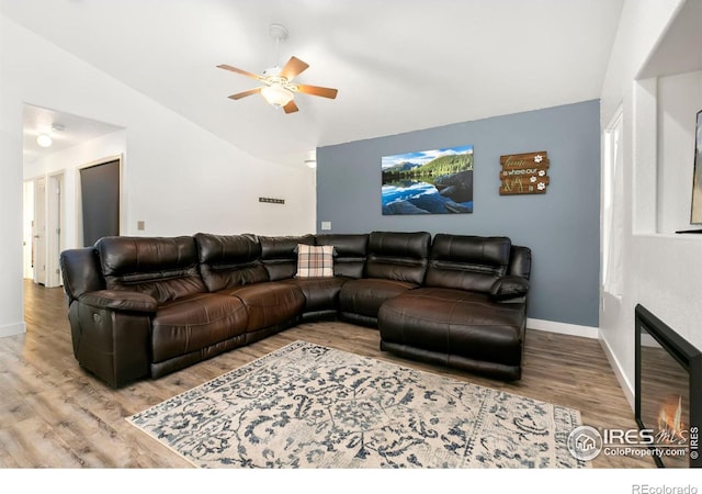 living room featuring hardwood / wood-style flooring, ceiling fan, and vaulted ceiling