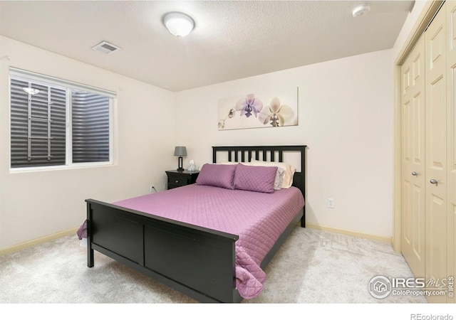 bedroom featuring a textured ceiling, light colored carpet, and a closet