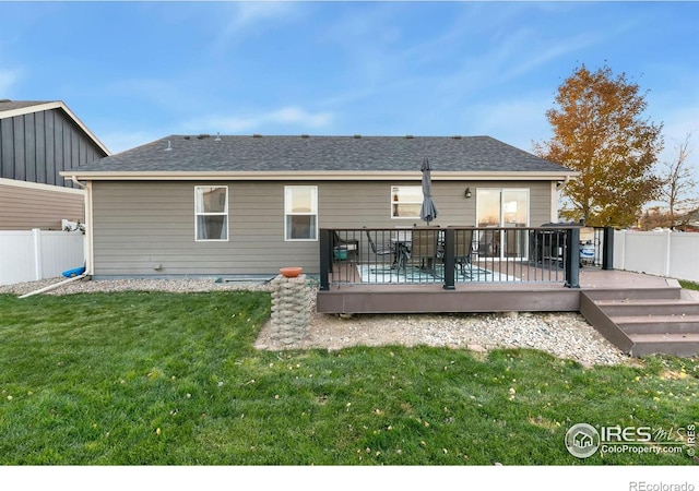 rear view of house featuring a lawn and a wooden deck