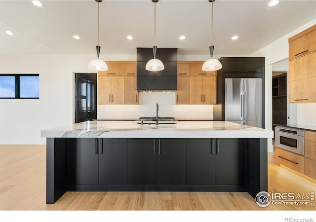 kitchen with a large island, hanging light fixtures, and light wood-type flooring