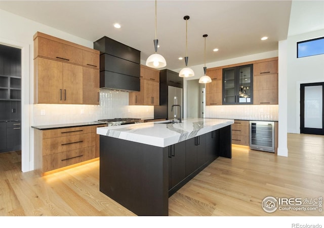 kitchen featuring pendant lighting, premium range hood, wine cooler, a large island, and light hardwood / wood-style floors