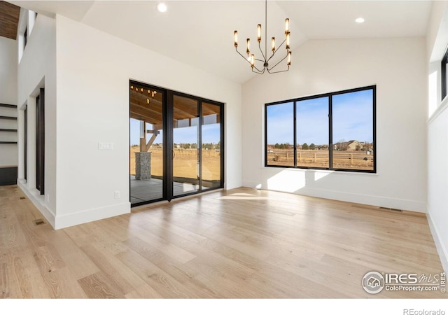 spare room with light hardwood / wood-style floors, lofted ceiling, and an inviting chandelier