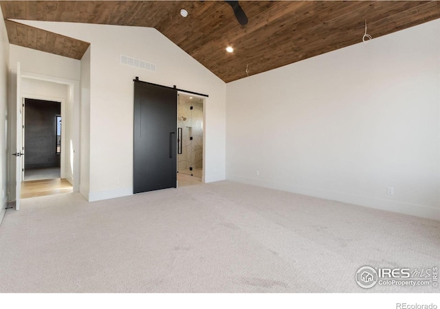 empty room featuring a barn door, light colored carpet, wood ceiling, and vaulted ceiling