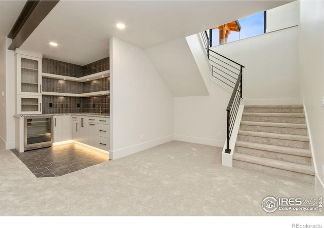 interior space featuring white cabinets, dark carpet, sink, and beverage cooler