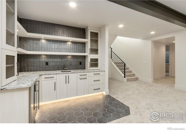 kitchen featuring carpet flooring, light stone counters, and sink