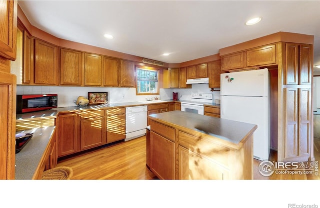 kitchen featuring light hardwood / wood-style flooring, a center island, white appliances, and sink