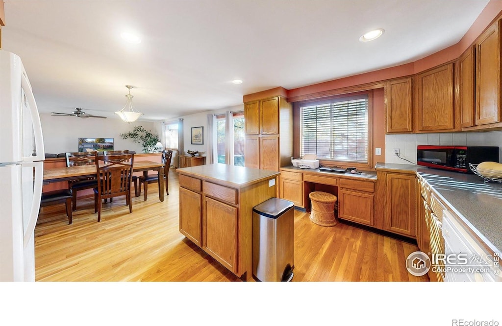 kitchen featuring ceiling fan, a center island, light hardwood / wood-style flooring, white fridge, and pendant lighting