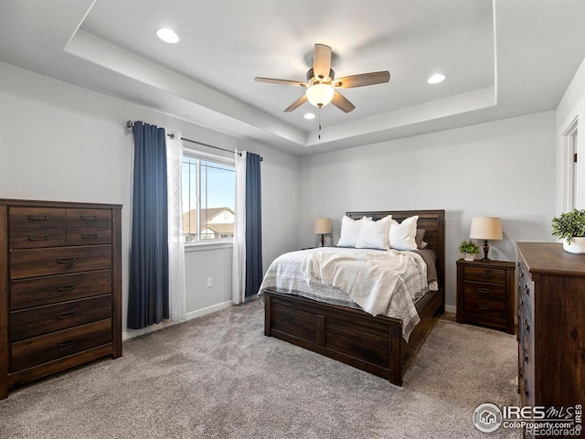 bedroom with ceiling fan, a raised ceiling, and light colored carpet