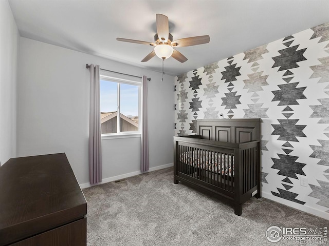 bedroom featuring ceiling fan, a nursery area, and light carpet