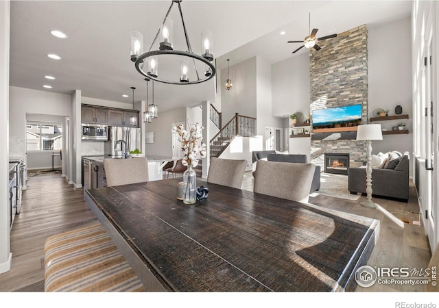 dining space featuring sink, ceiling fan with notable chandelier, dark hardwood / wood-style flooring, and a fireplace