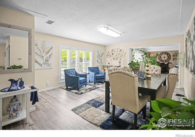 dining space featuring light hardwood / wood-style flooring and a textured ceiling