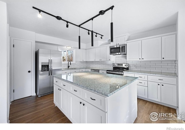 kitchen featuring dark hardwood / wood-style flooring, stainless steel appliances, a kitchen island, decorative light fixtures, and white cabinetry