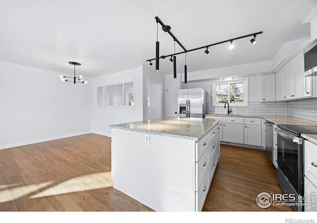 kitchen featuring stainless steel appliances, white cabinets, hardwood / wood-style floors, a kitchen island, and hanging light fixtures