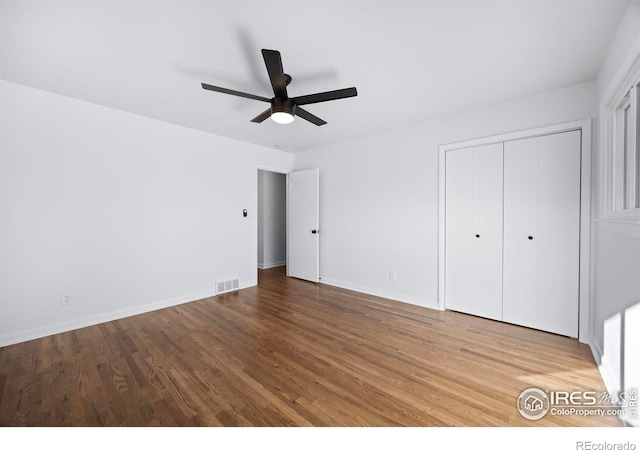 unfurnished bedroom with ceiling fan, a closet, and hardwood / wood-style flooring