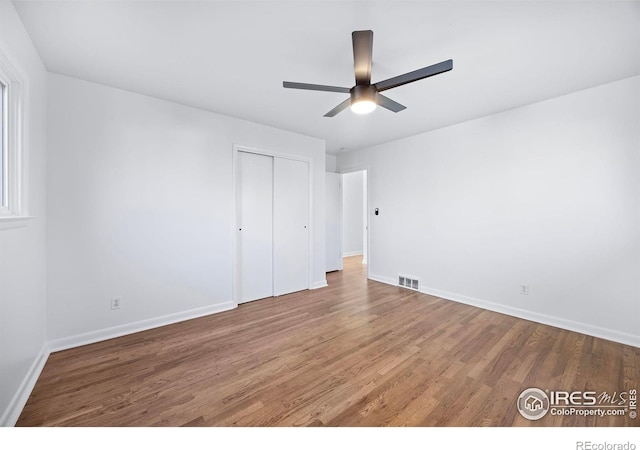 unfurnished bedroom with ceiling fan, a closet, and wood-type flooring