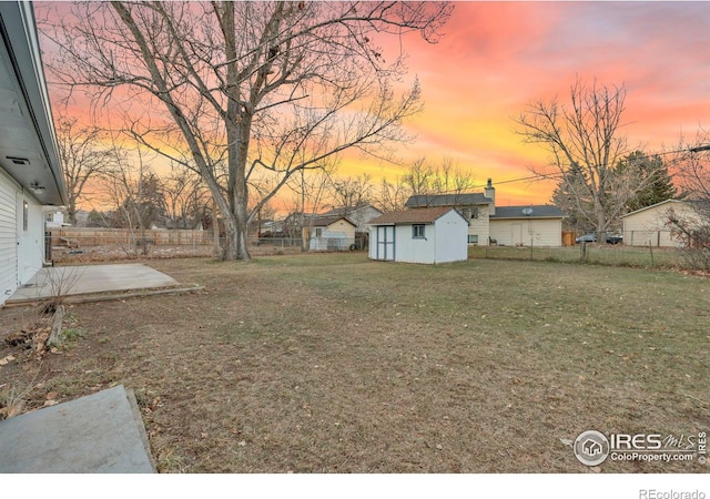 yard at dusk with a shed and a patio area