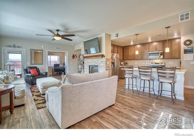 living room with a fireplace, light hardwood / wood-style floors, and ceiling fan