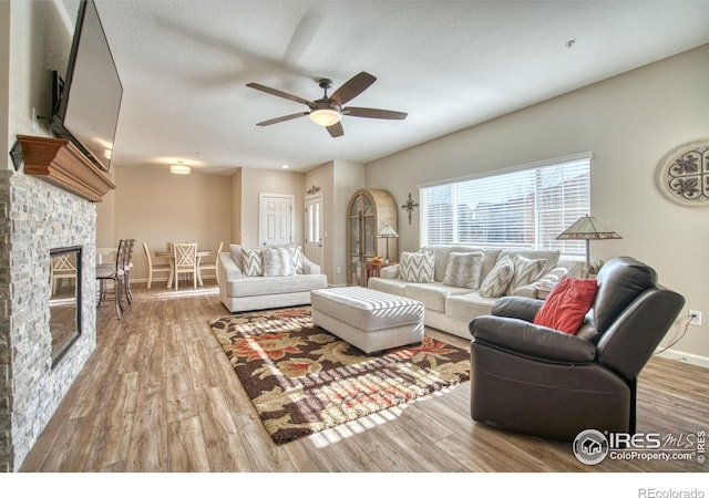 living room with hardwood / wood-style floors, ceiling fan, a fireplace, and a textured ceiling