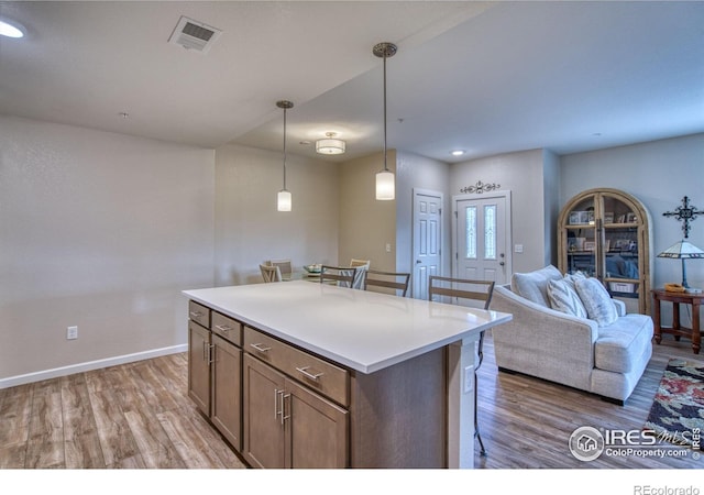 kitchen featuring a kitchen island, light wood-type flooring, hanging light fixtures, and a breakfast bar area