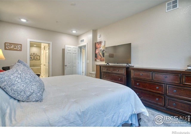 bedroom with ensuite bath and carpet floors