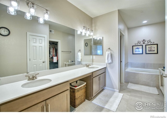 bathroom with vanity, a relaxing tiled tub, and tile patterned floors