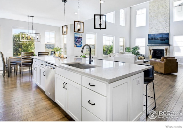 kitchen with pendant lighting, sink, white cabinets, a center island with sink, and stainless steel dishwasher