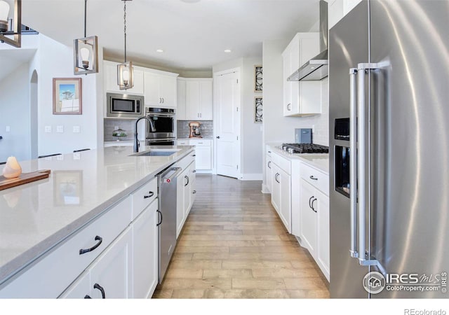 kitchen featuring stainless steel appliances, sink, pendant lighting, and white cabinets