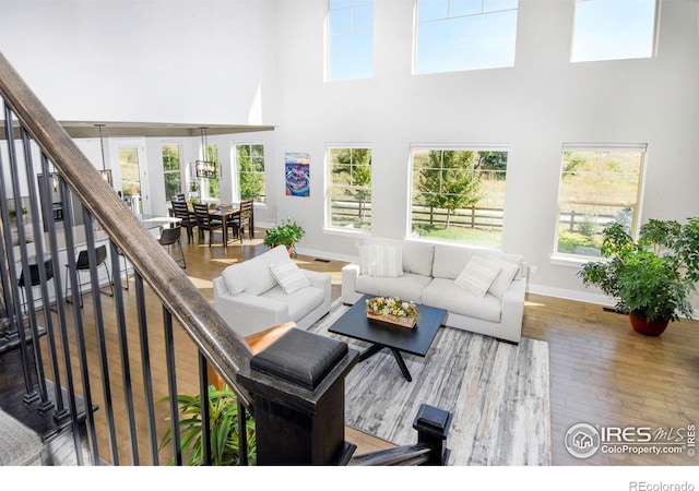 living room with hardwood / wood-style floors, plenty of natural light, and a high ceiling