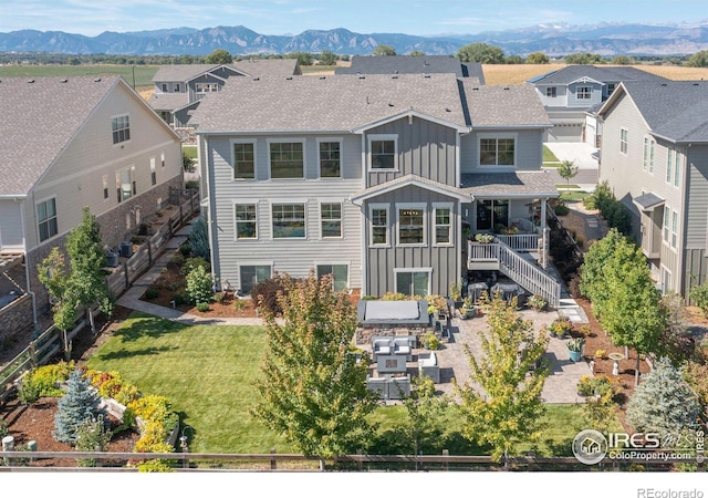 rear view of house featuring a mountain view and a yard