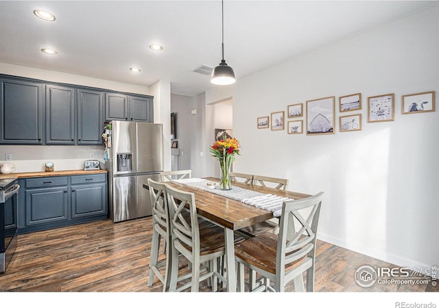 kitchen featuring pendant lighting, wood counters, stainless steel appliances, and dark wood-type flooring