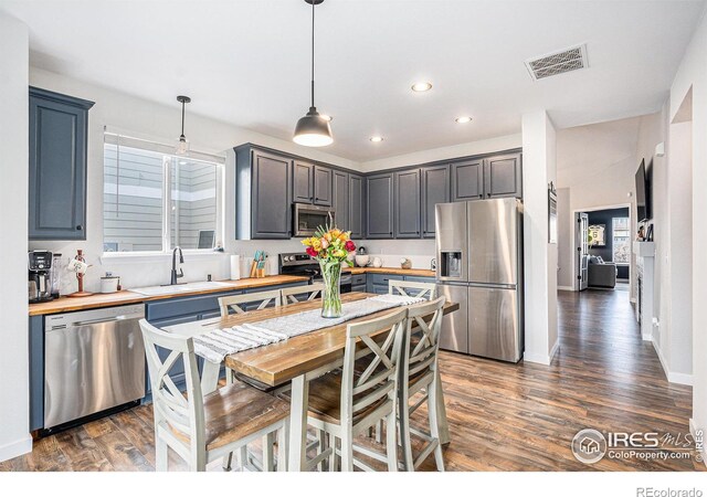 kitchen with sink, decorative light fixtures, dark hardwood / wood-style flooring, and stainless steel appliances