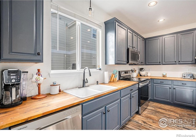 kitchen featuring dark hardwood / wood-style flooring, sink, appliances with stainless steel finishes, and wooden counters