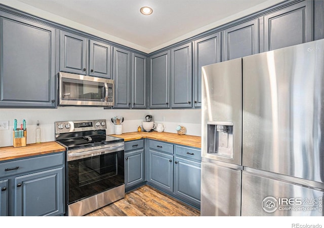 kitchen with hardwood / wood-style flooring, wooden counters, and appliances with stainless steel finishes