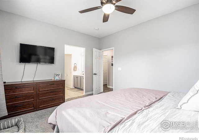 bedroom featuring light carpet, ensuite bathroom, and ceiling fan