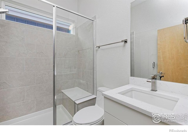 bathroom featuring a shower with door, vanity, and toilet