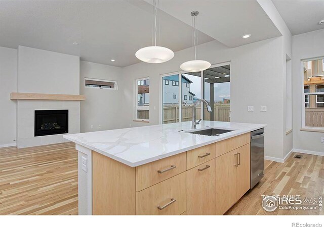 2292 Star Hill St, Longmont, CO 80503 - kitchen featuring a sink, light brown cabinets, dishwasher, light wood finished floors, and a center island with sink