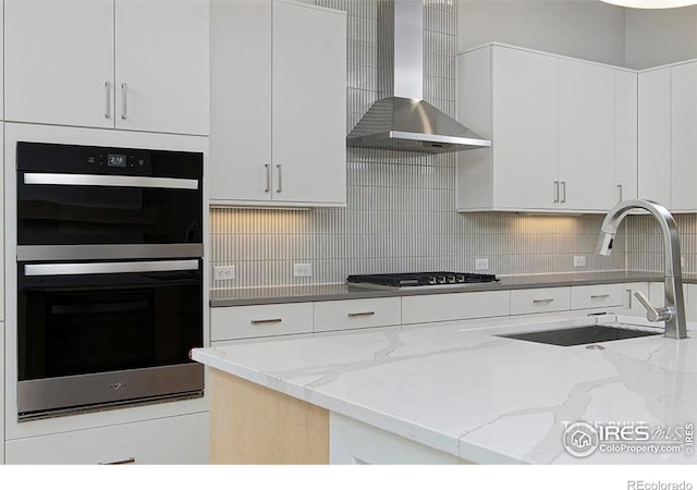 2292 Star Hill St, Longmont, CO 80503 - kitchen with double wall oven, stainless steel gas cooktop, a sink, wall chimney range hood, and white cabinetry